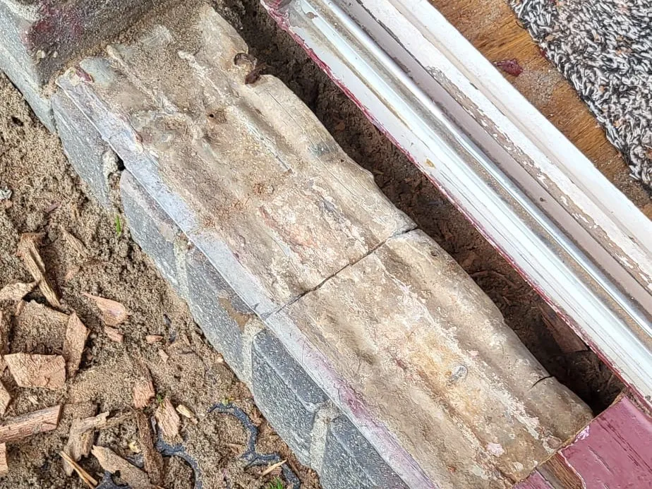 Onderdorpel van een kozijn met vermolmd, uitgehold hout tot op het metselwerk